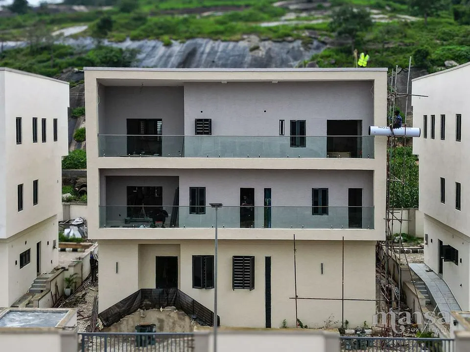 The front of the 5-bedroom standalone mansion in Katampe Extension, Abuja, seen from the street with its own gated compound wall and the Katampe rock outcrop rising behind it